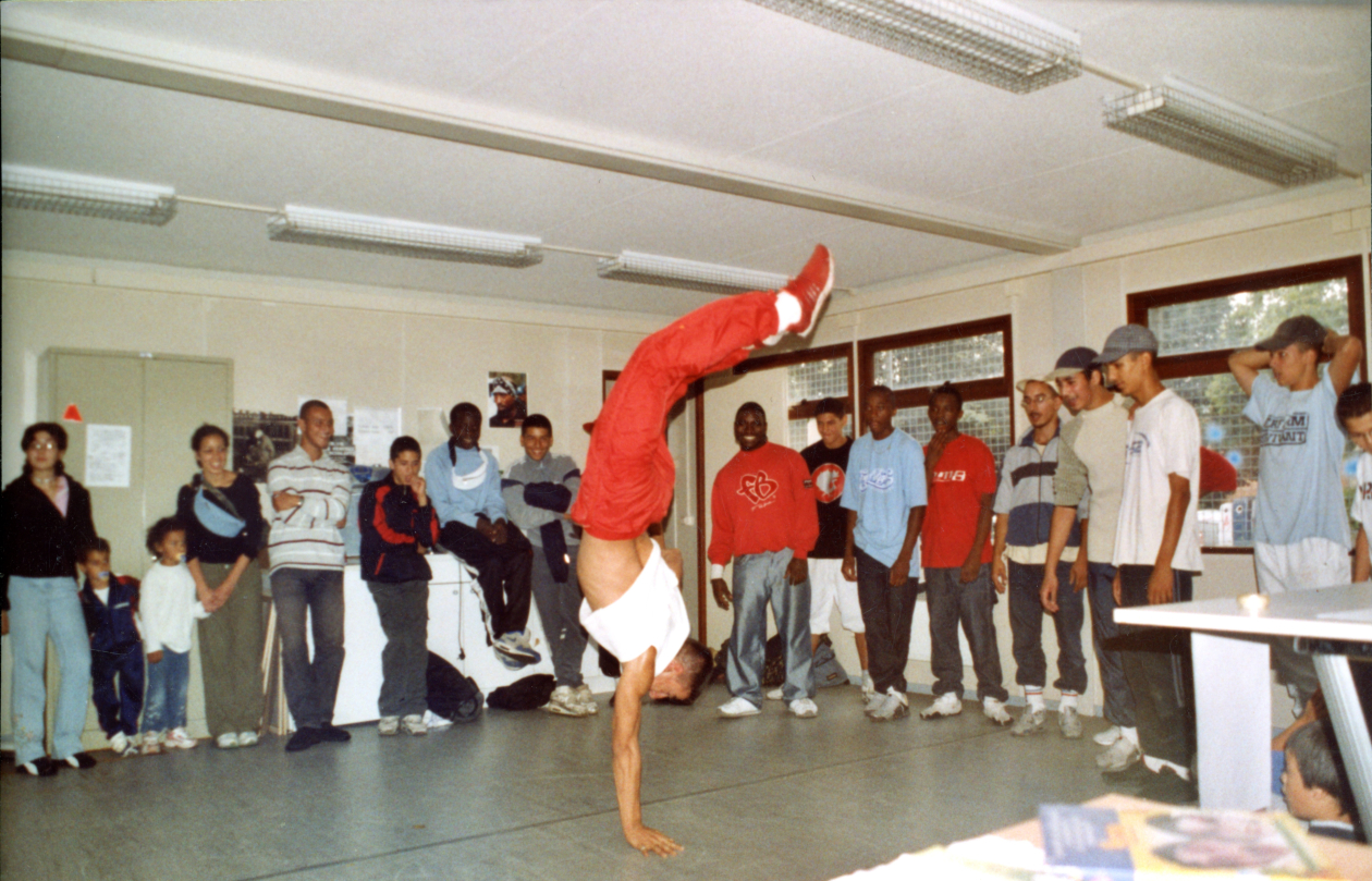 Démonstration de break dance dans le préfabriqué à l’occasion de la fête de clôture des vacances d’été 2003. Photographie de Raquel Pereira, La Maison des enfants.
